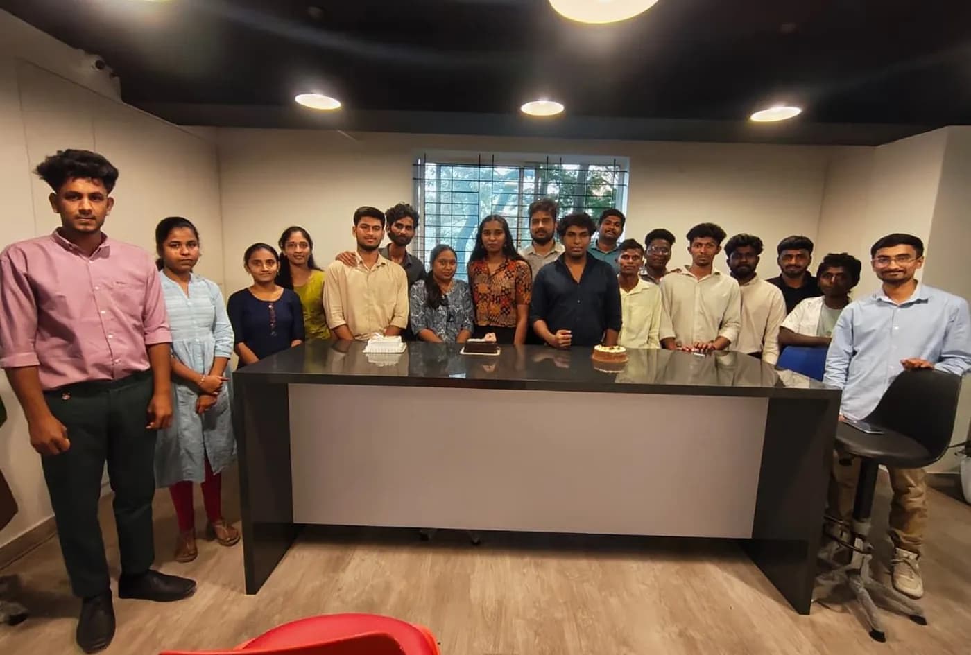 The Brightnodes team gathered around the pantry counter with three celebration cakes